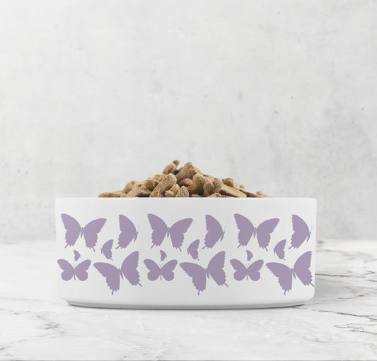 Hand drawn purple lavender butterflies are printed on a white ceramic pet dish.