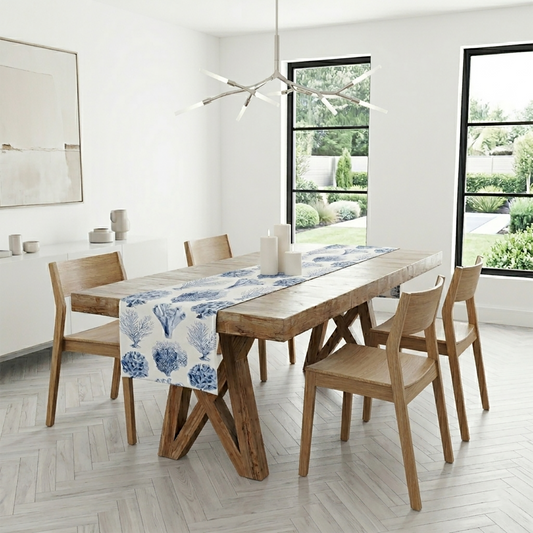 Dining room with wooden table and chairs, blue and white coral print table runner, and large windows.