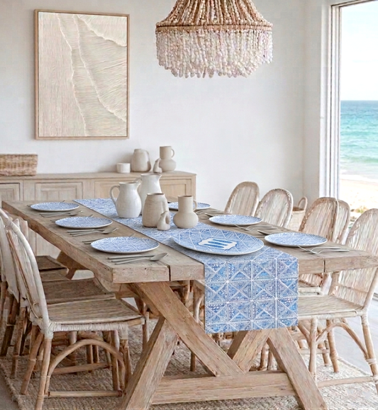 Dining room with wooden table and chairs, coastal blue and white tile plates and decor, and view of ocean.