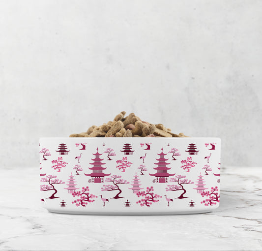 Pink chinoiserie dog food or cat water bowl features hand drawn bonsai trees, pagodas and crane birds.