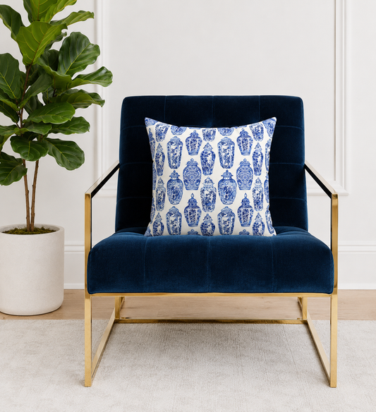 Navy blue armchair with a decorative pillow featuring blue and white ginger jars pattern, next to a potted plant.