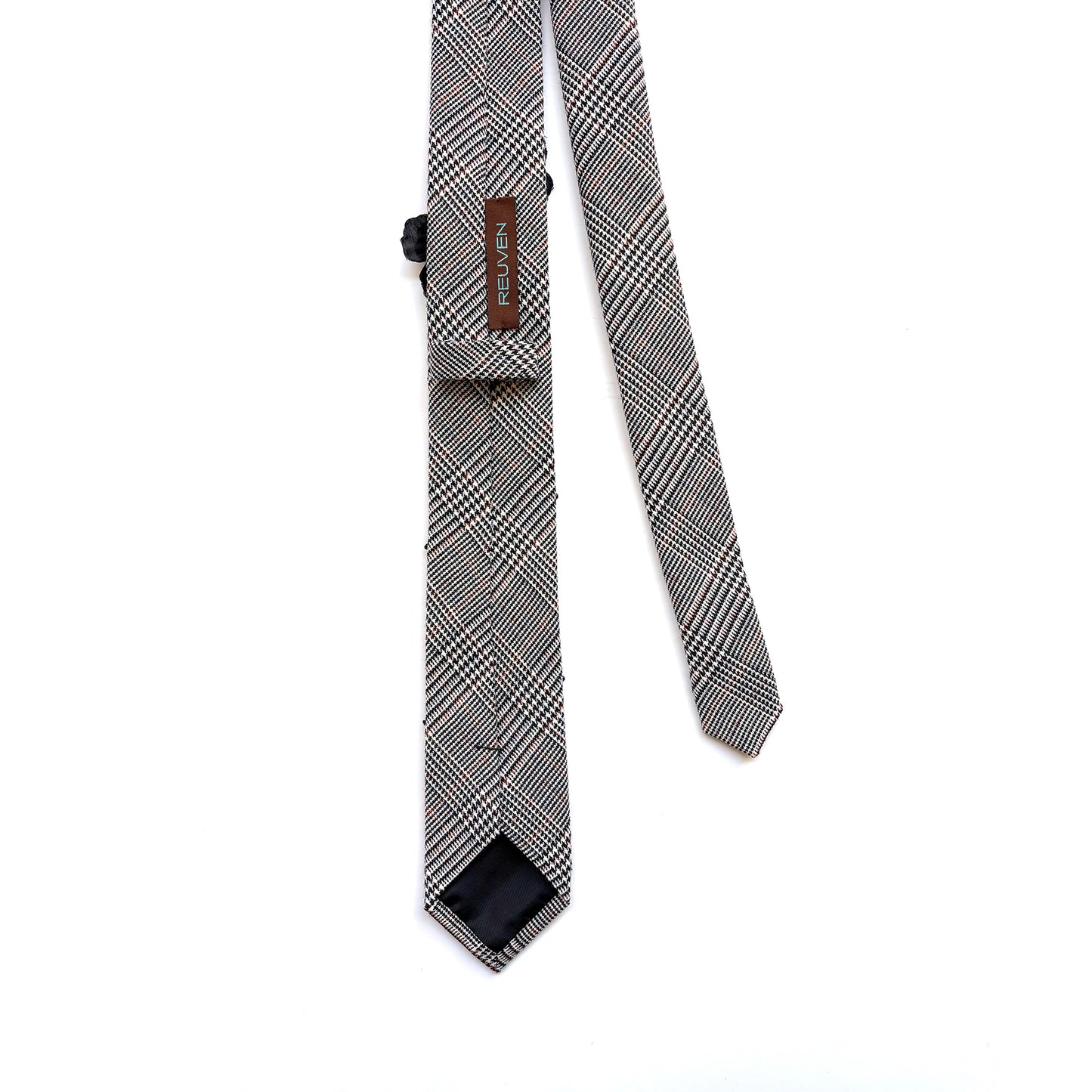 Black and white houndstooth plaid skinny necktie backside with brand label REUVEN