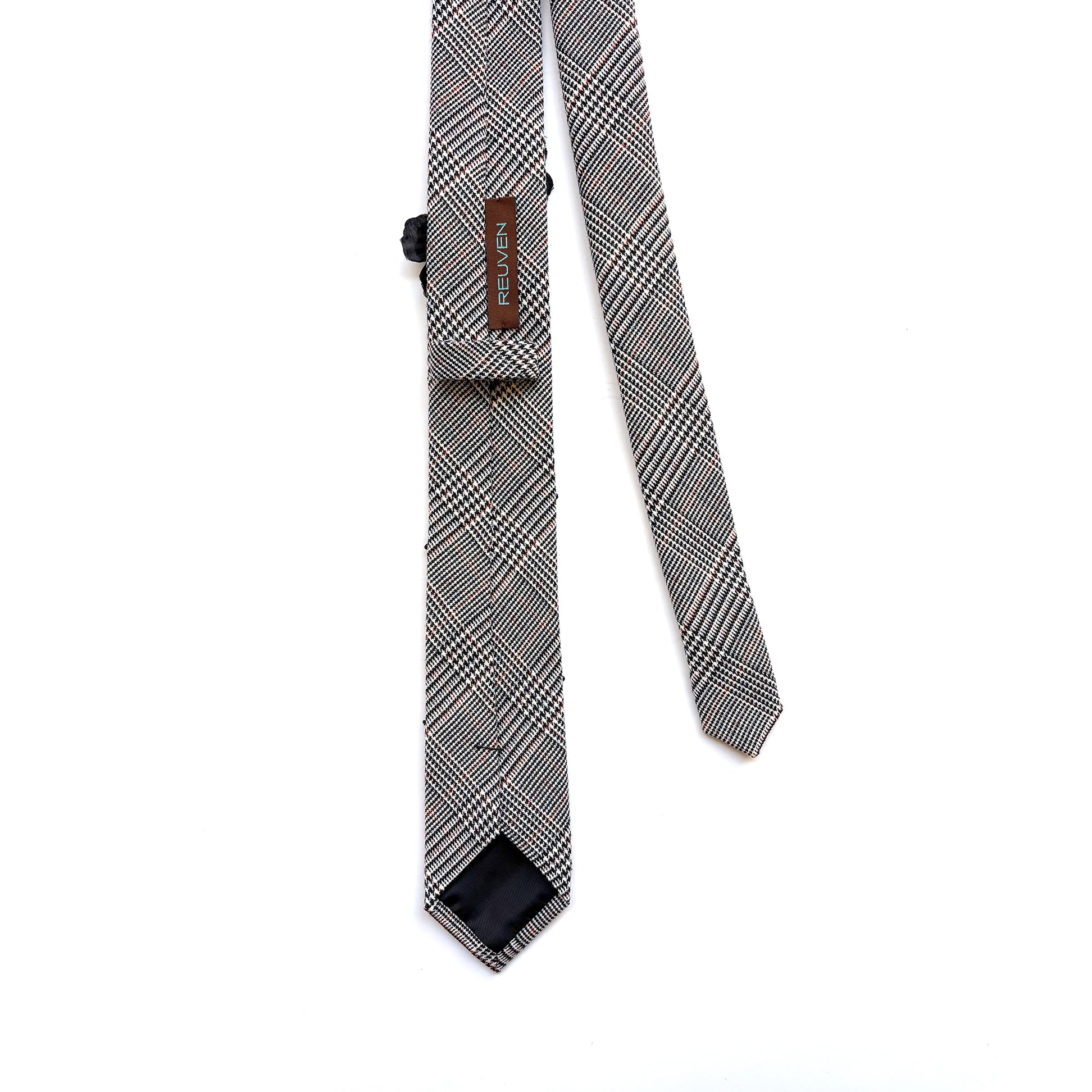 Black and white houndstooth plaid skinny necktie backside with brand label REUVEN