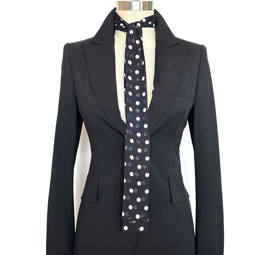 Black suit jacket with a polka dot blunt-edge neck tie on a mannequin against a white background