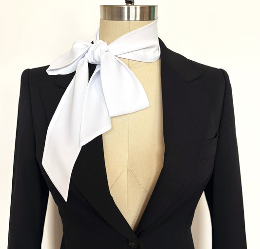 Black blazer with an oversized white bow tie on a mannequin against a white background
