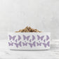 Hand drawn purple lavender butterflies are printed on a white ceramic pet dish.