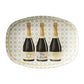 White oval serving platter features a graphic of three watercolor illustrated champagne bottles, each with a unique Hanukkah-inspired label:  one at the center is personalized with a name or phrase of your choice, one with a Star of David in shimmering gold glitter, and one featuring a glittery golden menorah. The entire tray is finished with an all-over Star of David print background in gold for an extra festive touch.