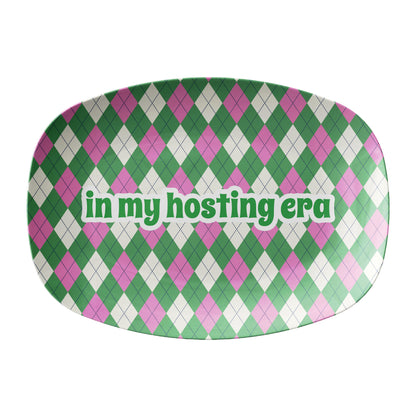 Green and pink argyle pattern printed on a serving platter with text that says in my hosting era.