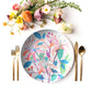 Colorful honeysuckle floral print plate with cutlery and flowers on a white background
