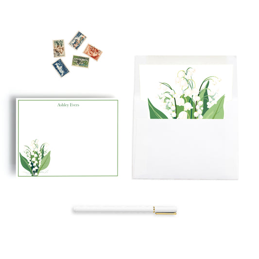 Personalized lily of the valley note cards with floral design, stamps, and a pen on a white background. envelope is hand lined with floral print paper.