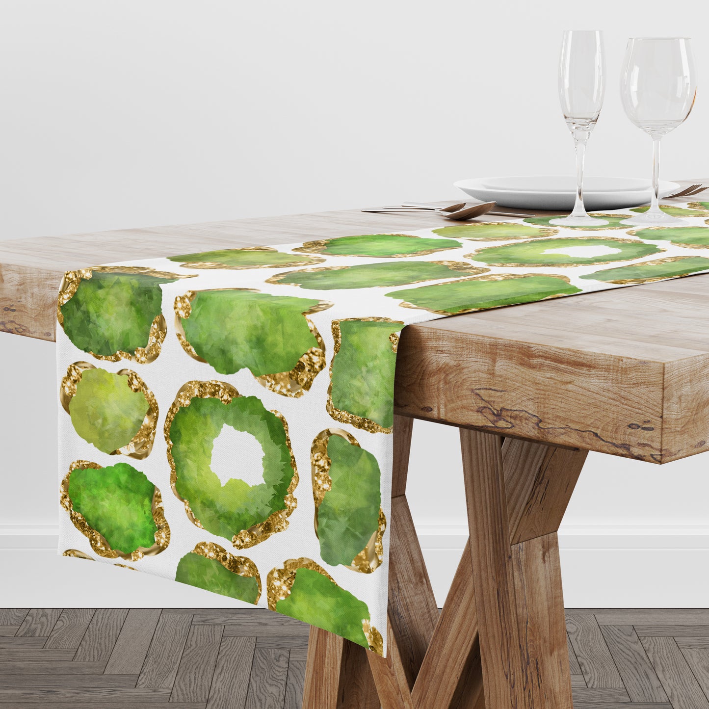 White table runner with green and gold crystal gemstones printed all over it. Shown on a wood table.
