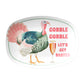 White oval serving platter features a print of a pink and green turkey and pink bubbly champagne flute. Pink text on the platter says Gobble Gobble Let's get basted.
