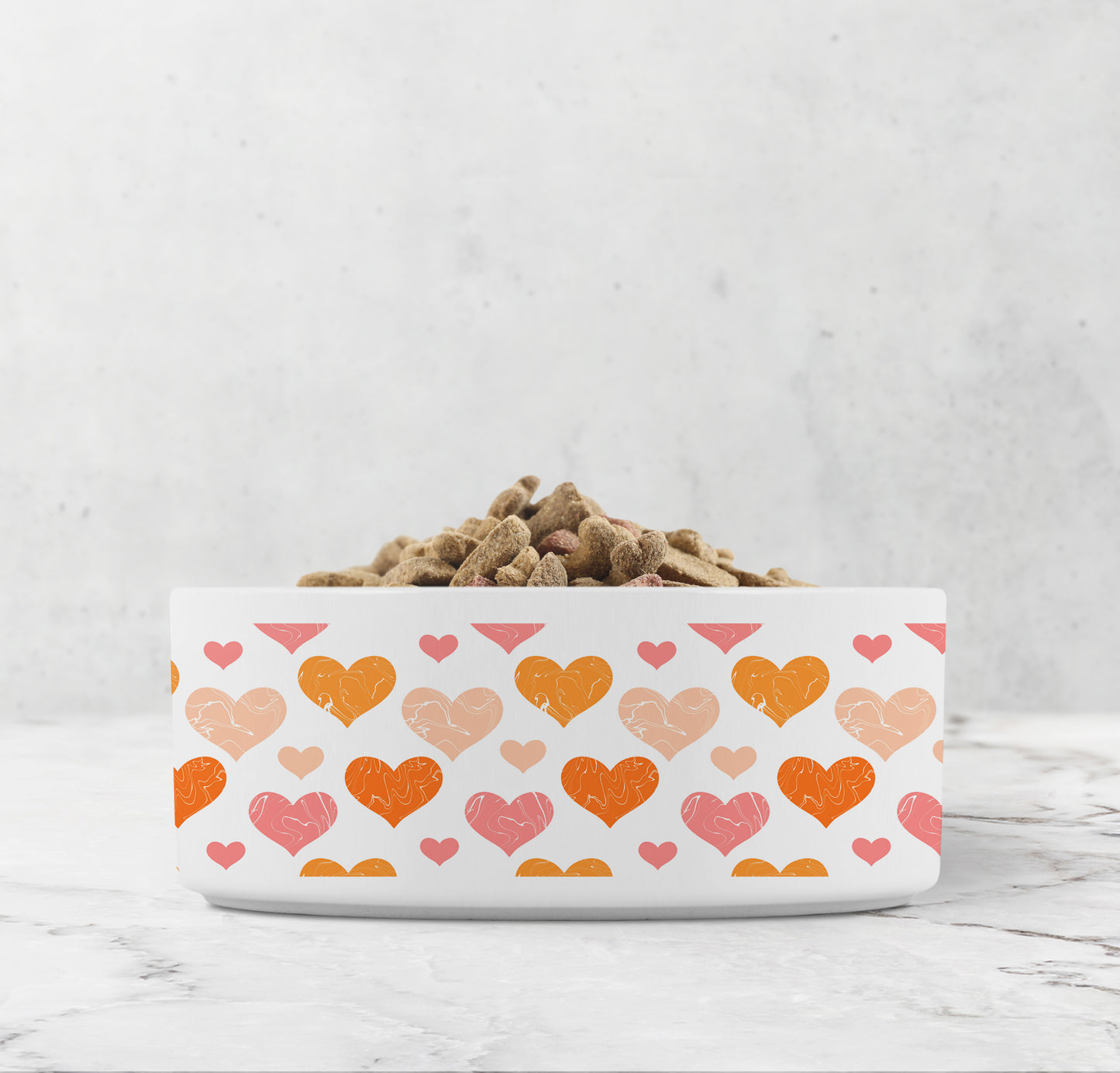 Hearts pattern in orange and pink are printed all around white ceramic pet dish