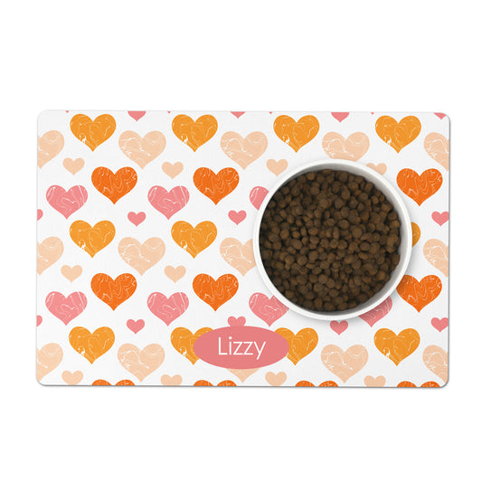 White pet placemat has orange and pink hearts printed all over it, add any custom name or text to personalize as a gift for your dog or cat.