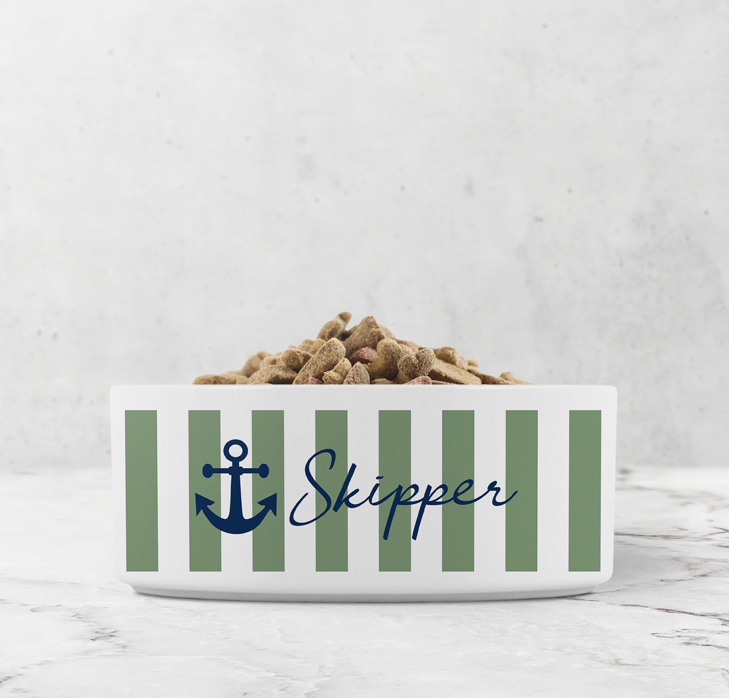 White ceramic pet bowl with sage green nautical stripes, navy blue anchor design and custom pet name on marble surface