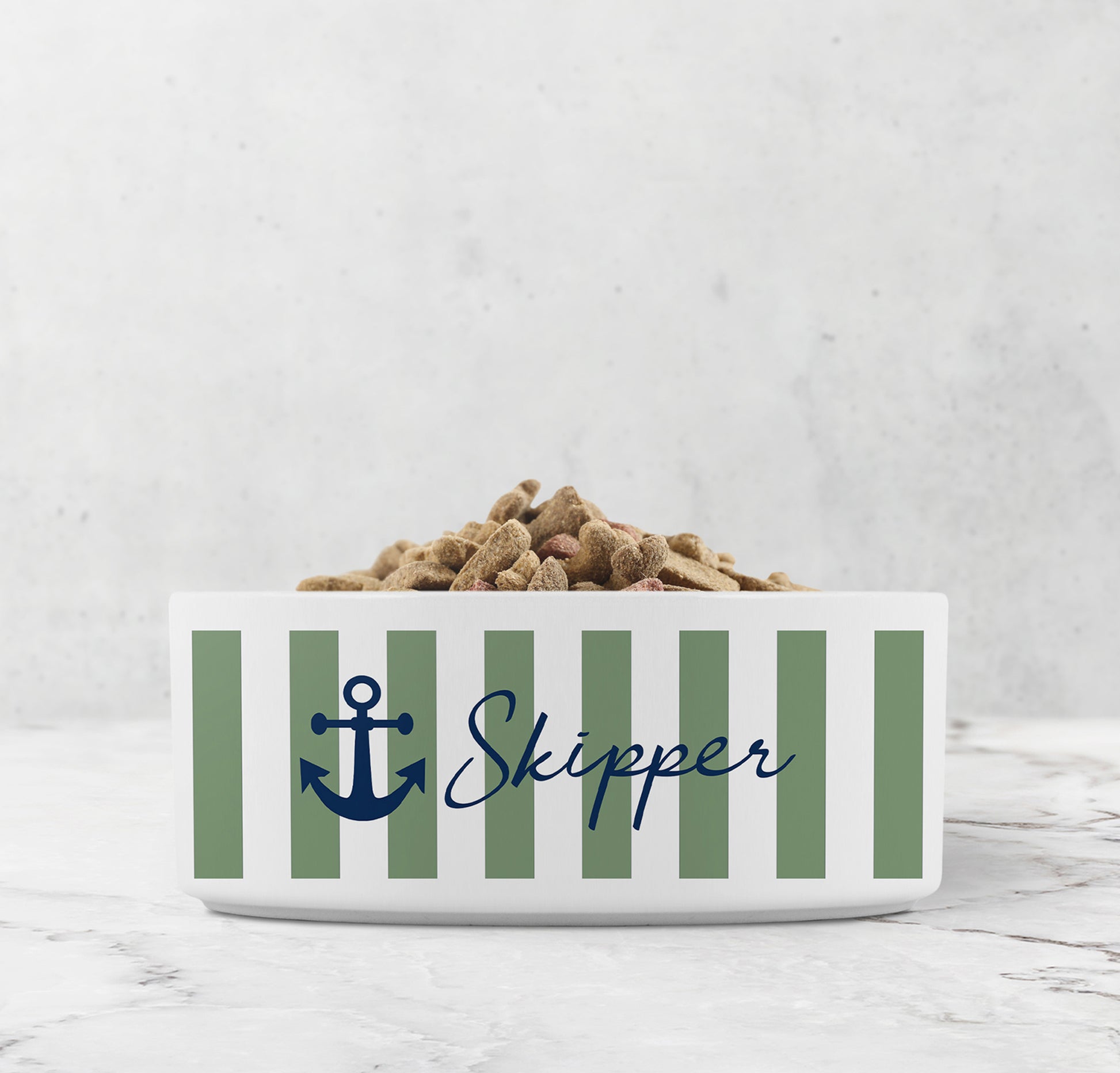 White ceramic pet bowl with sage green nautical stripes, navy blue anchor design and custom pet name on marble surface