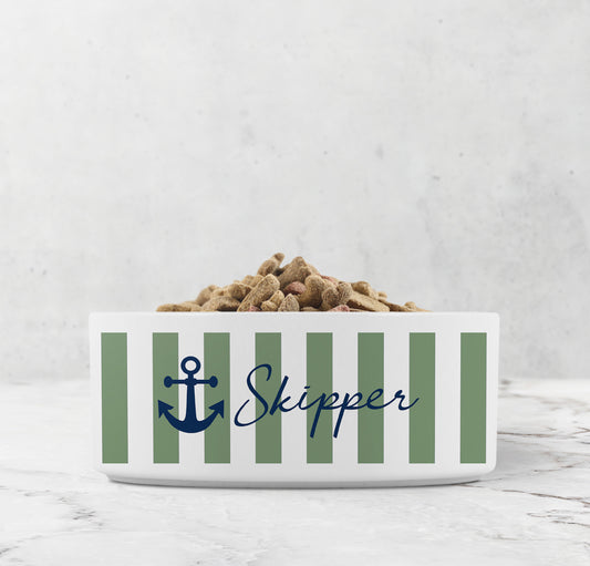 White ceramic pet bowl with sage green nautical stripes, navy blue anchor design and custom pet name on marble surface