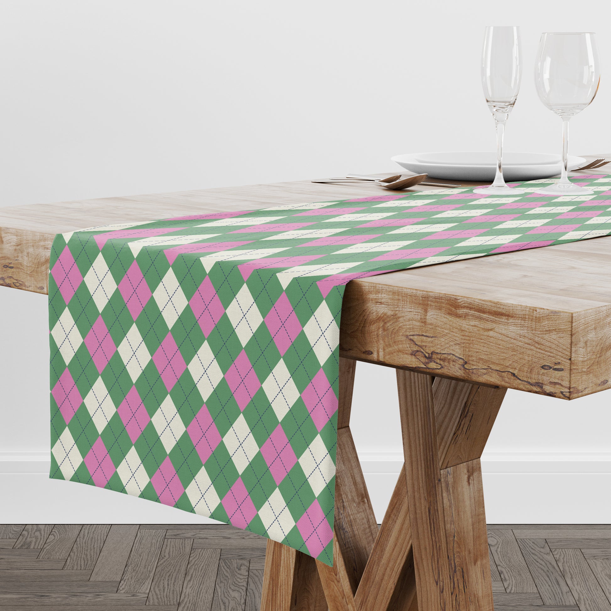 Table runner with green and pink diamond argyle pattern on a wooden table.