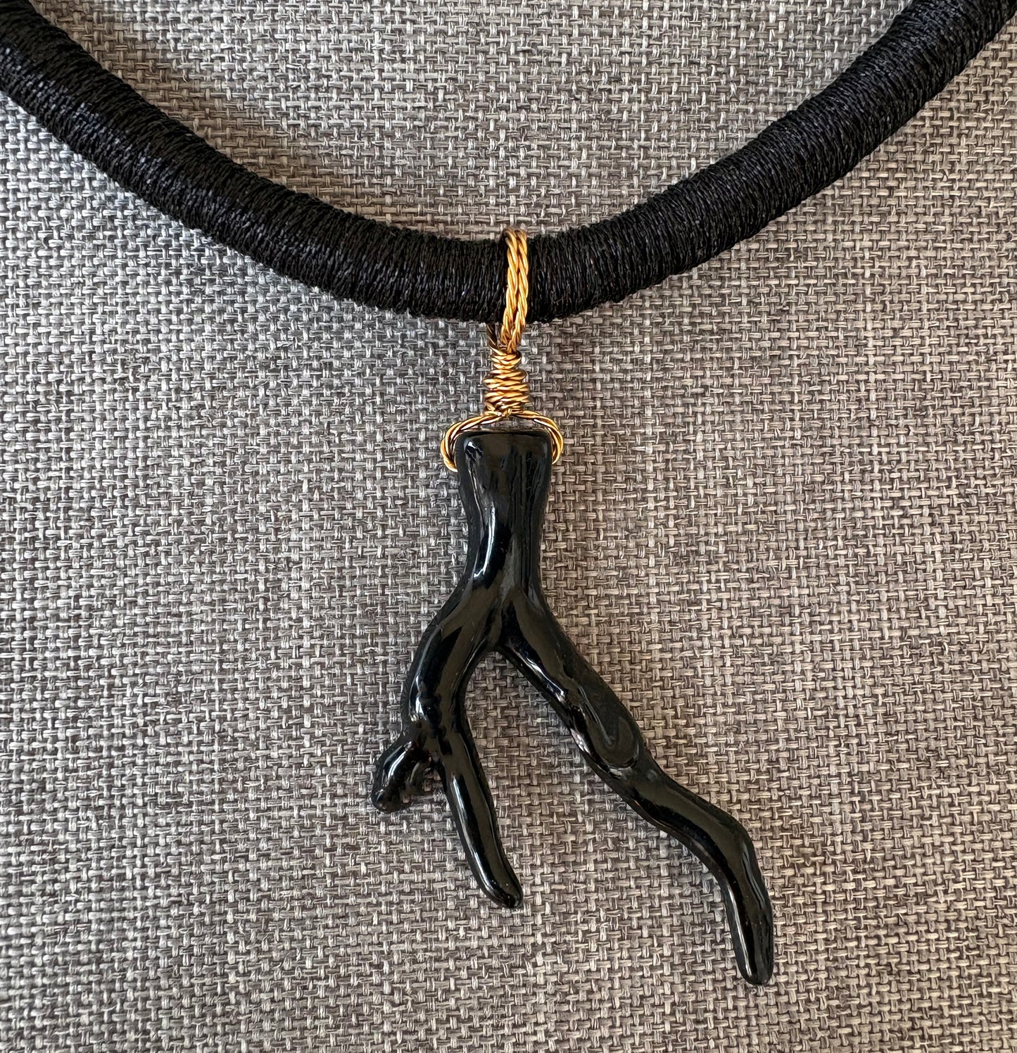 Black sea coral branch pendant necklace on a textured gray background
