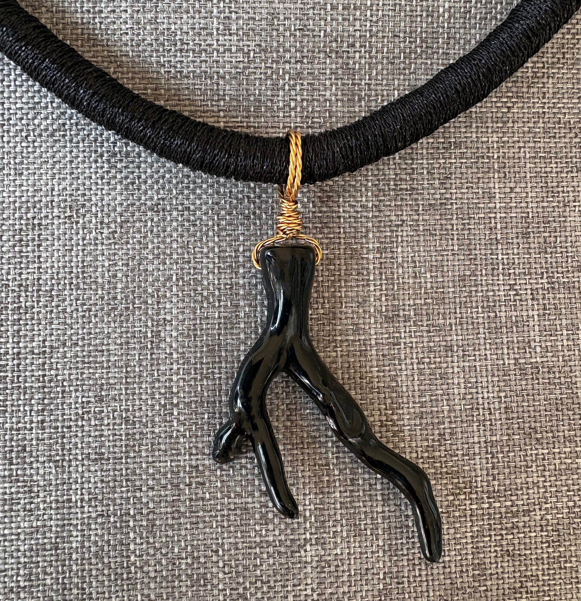 Black sea coral branch pendant necklace on a textured gray background