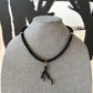 Black rope necklace with a sea coral branch pendant on a gray mannequin against a black and white abstract background