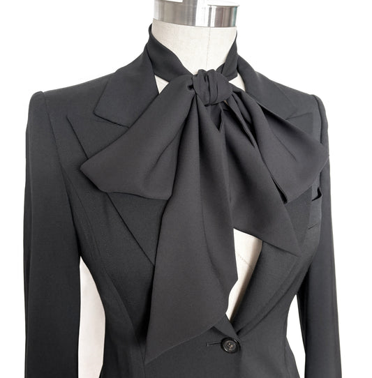 Long black scarf tied in oversize dramatic bow on mannequin with black jacket