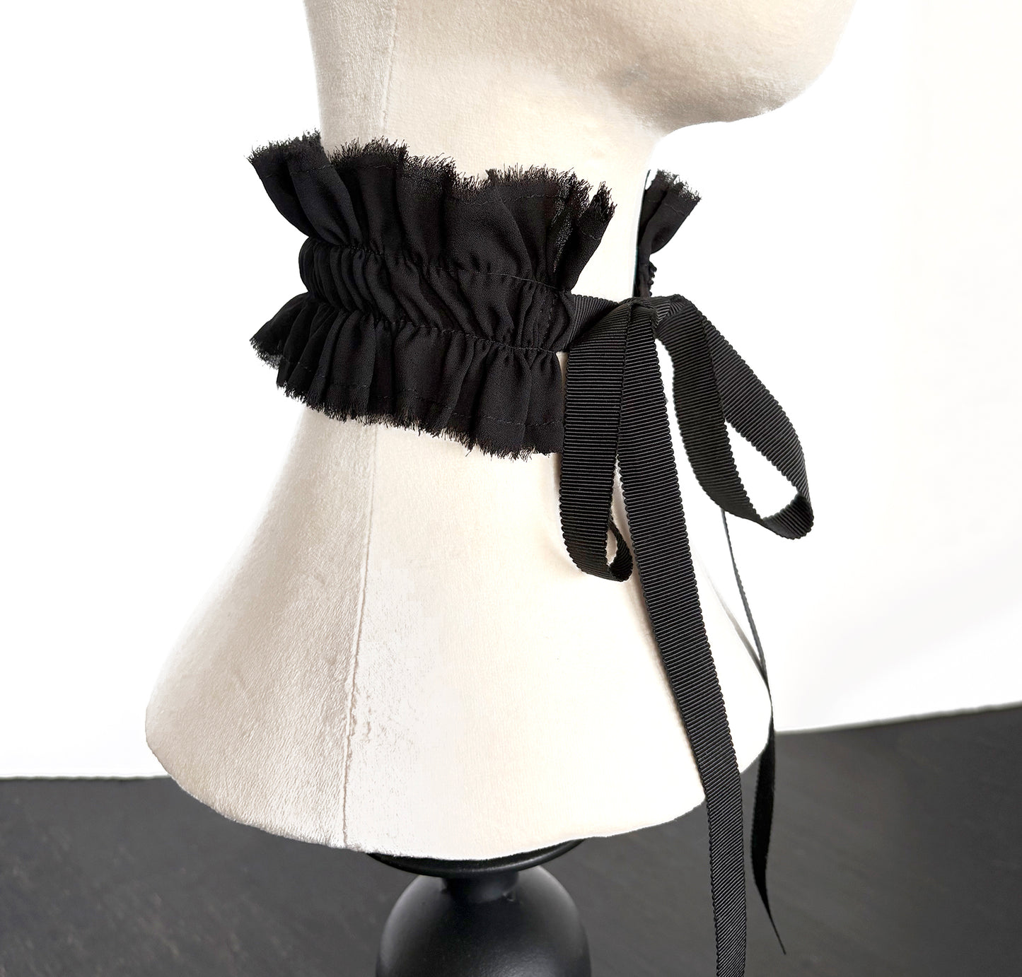 Black ruffled collar choker with ribbons tied in bow on a mannequin neck