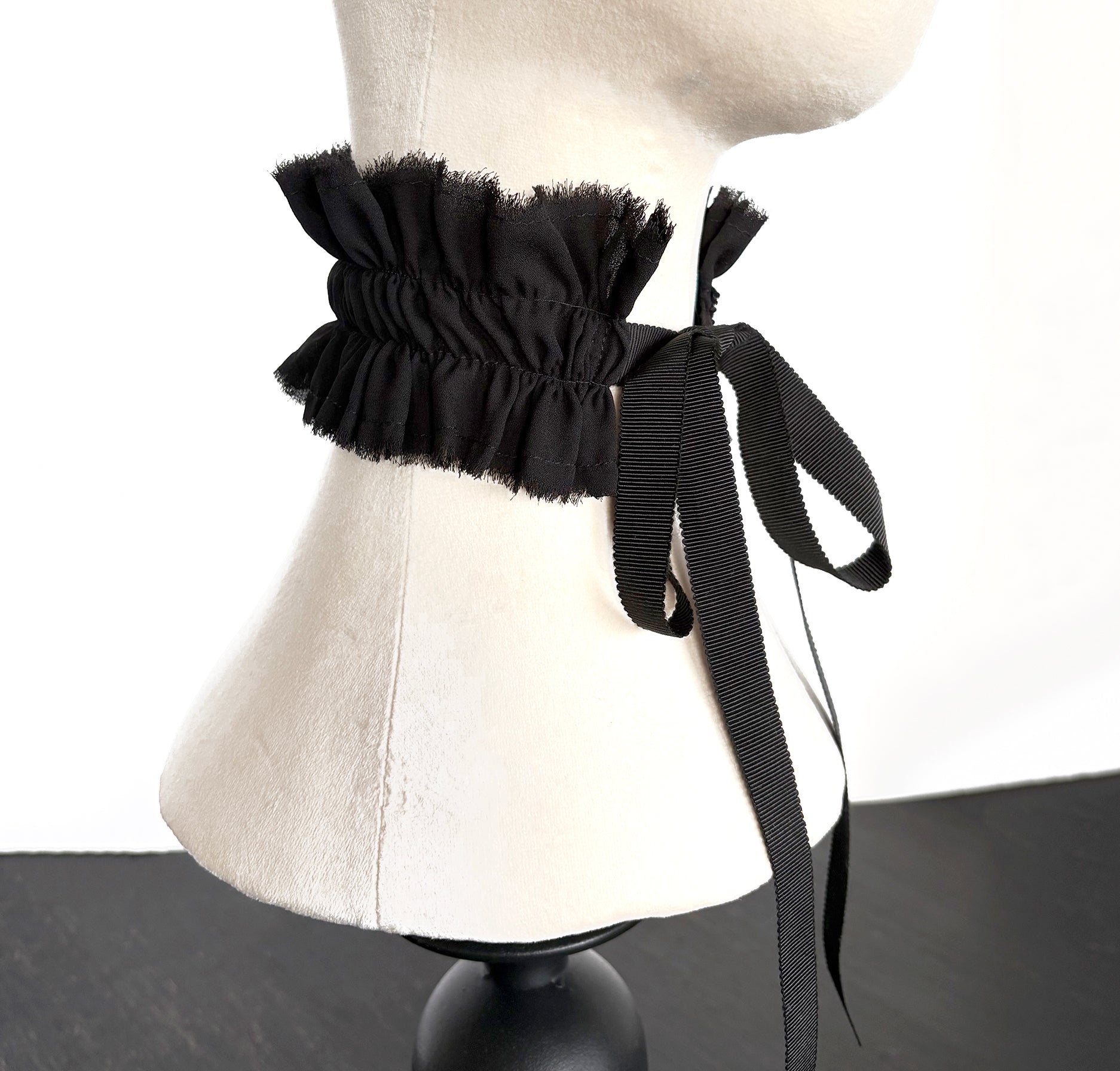 Black ruffled collar choker with ribbons tied in bow on a mannequin neck