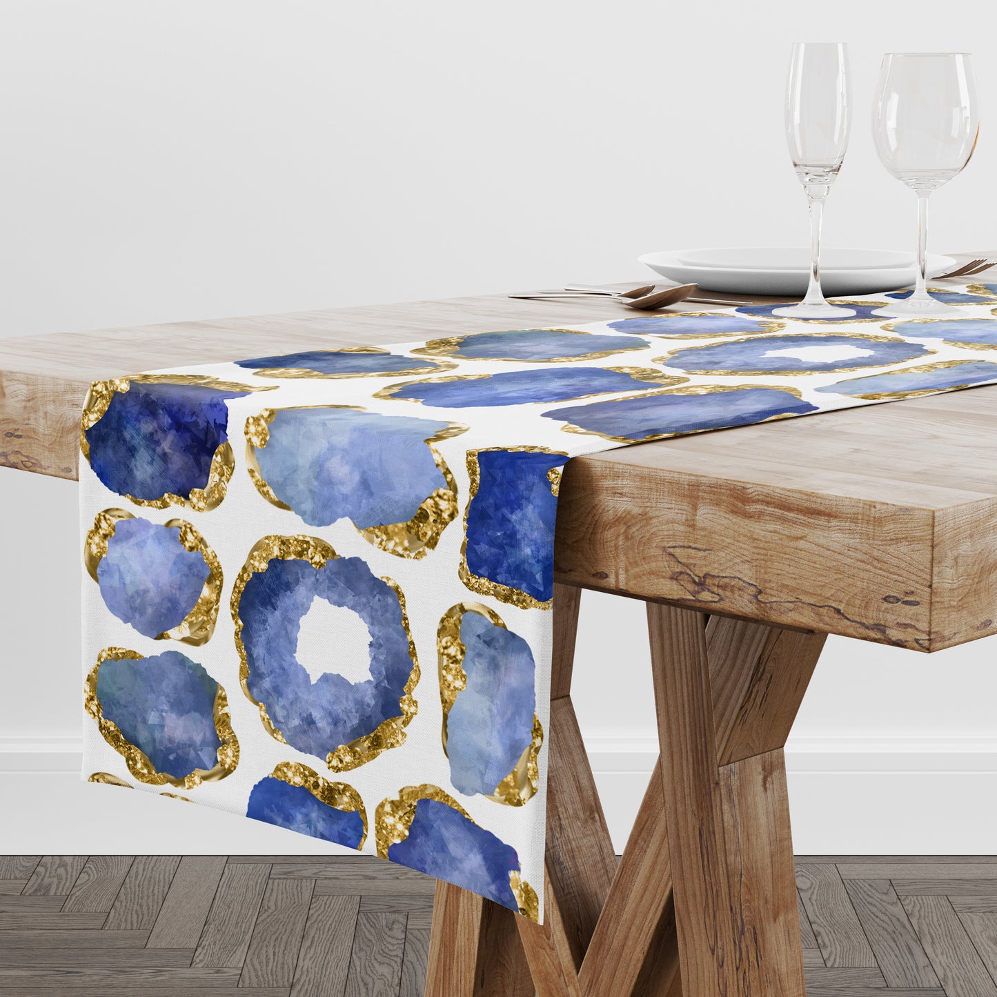 White table runner with blue sapphire and gold crystal gemstones printed all over it. Displayed on a wood table.