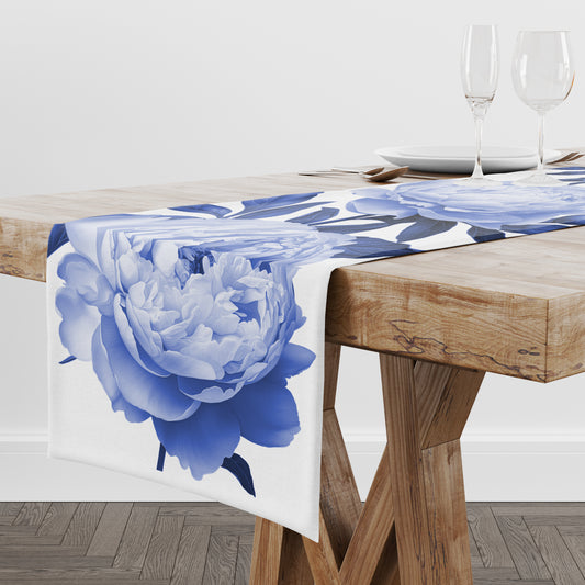 Bold blue peony flower print on white table runner linen draped on a wooden dining table