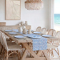 Dining room with wooden table and chairs, coastal blue and white tile plates and decor, and view of ocean.