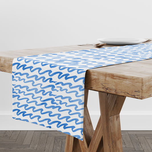 Blue and white table runner with hand painted wavy stripes on wood table.