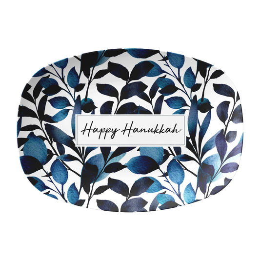 Decorative plate with blue leaf pattern and 'Happy Hanukkah' text on a white background