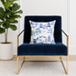 Navy blue armchair with a decorative pillow featuring a blue and white toile pattern, next to a potted plant.