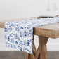 Table runner with blue and white chinoiserie toile pattern on a wooden table