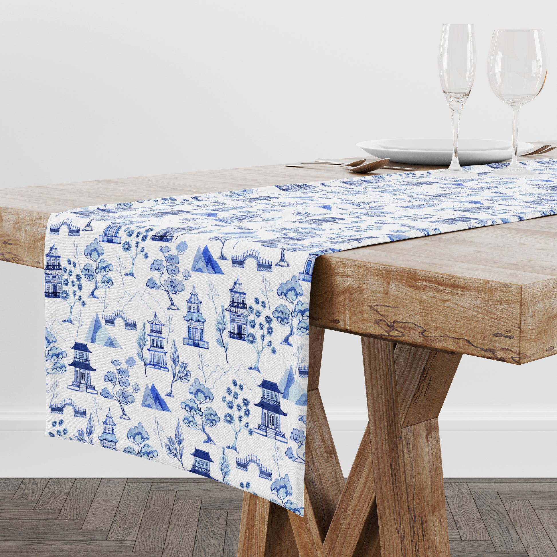 Table runner with blue and white chinoiserie toile pattern on a wooden table