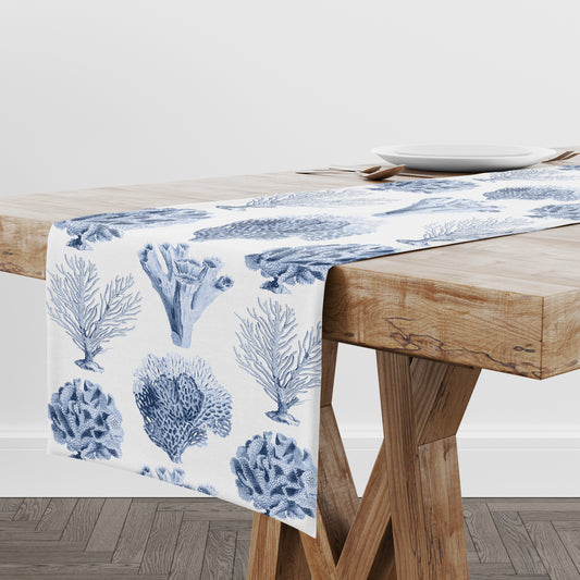 Table runner with blue coral pattern on white shown on a wooden table