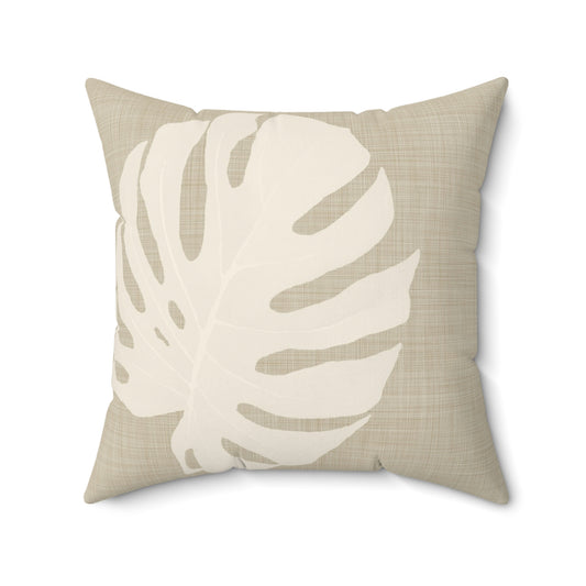 Beige square throw pillow with large ivory monstera leaf print.