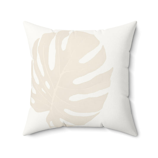 Square white pillow with large modern monstera leaf print in cream.