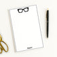 Chunky hipster eyeglasses icon print and custom name on a personalized paper stationery note pad with scissors and pen.