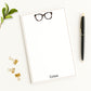 Personalized notepad desk stationery with tortoiseshell eyeglasses design and custom name shown with office accessories and green leaf.