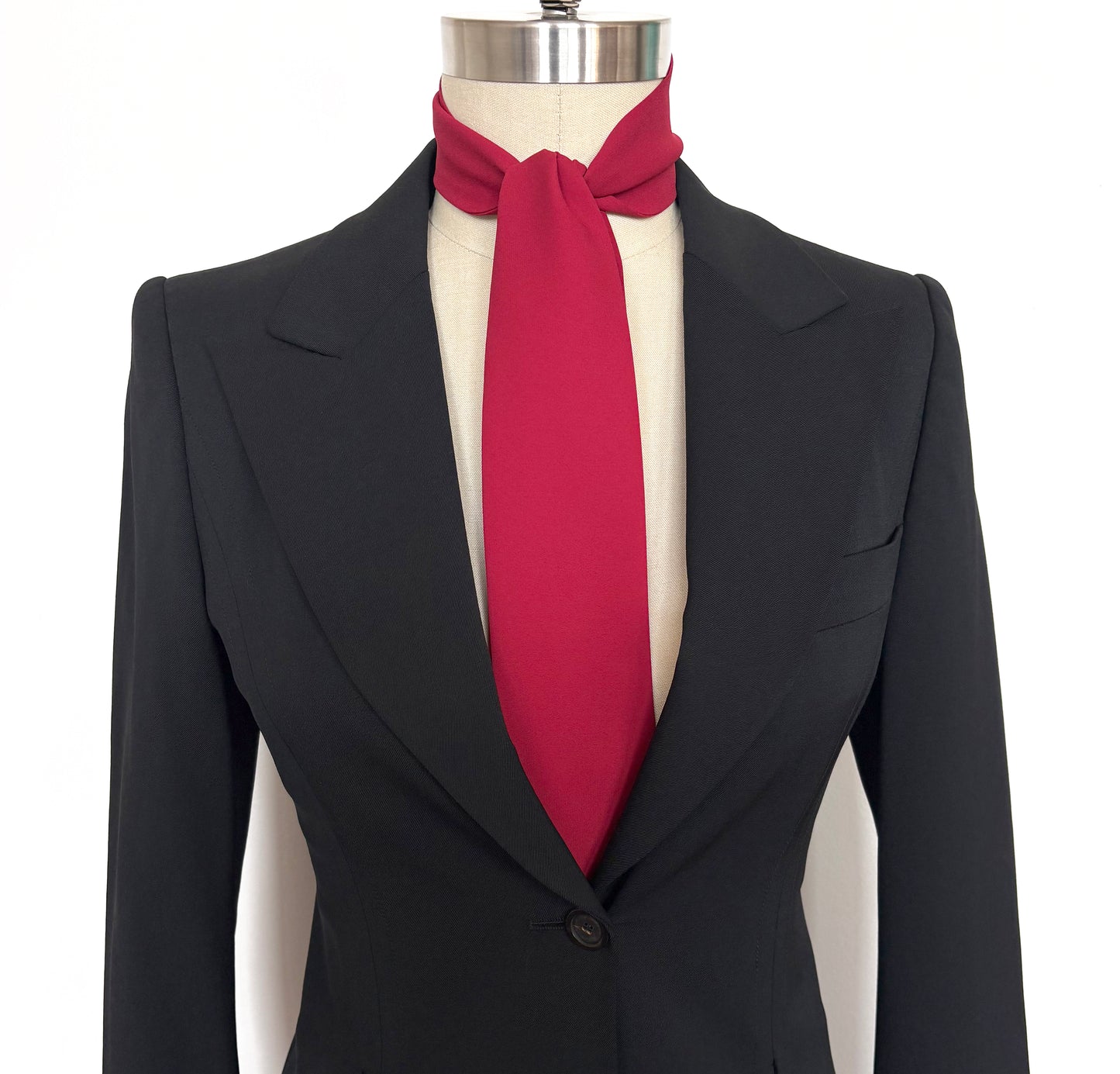 Black suit jacket with a red necktie cravat on a mannequin against a white background