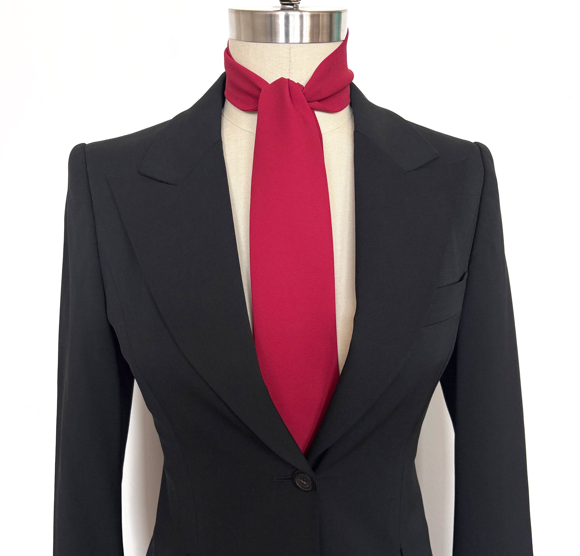 Black suit jacket with a red necktie cravat on a mannequin against a white background