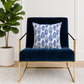 Navy blue armchair with a decorative pillow featuring blue and white ginger jars pattern, next to a potted plant.