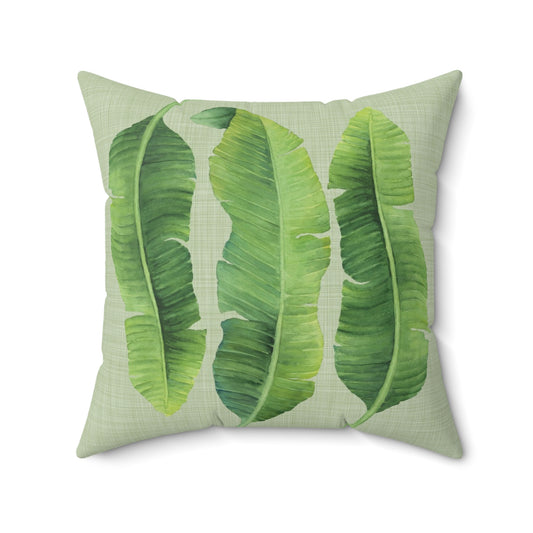 Square throw pillow with a banana leaves design set against a textured linen-effect print on white background