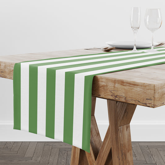 Green and white striped table runner on a wooden table with glasses in the background.
