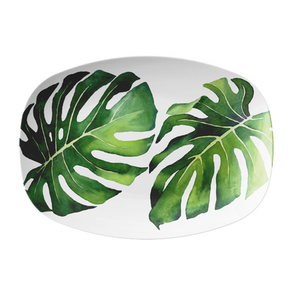 Oval white platter with green monstera leaf pattern on a white background