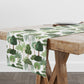 Tropical tree print table runner in green and white on wood farmhouse style dining table.