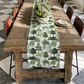 Dining table with a island-themed table runner and chairs in a room with checkered floor.