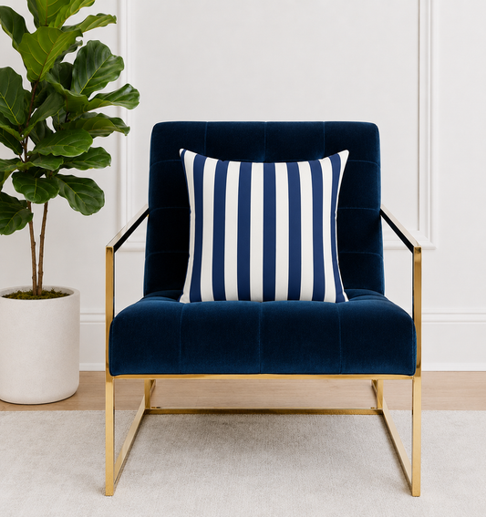 Navy blue armchair with a navy blue and white striped pillow in a room with a plant.